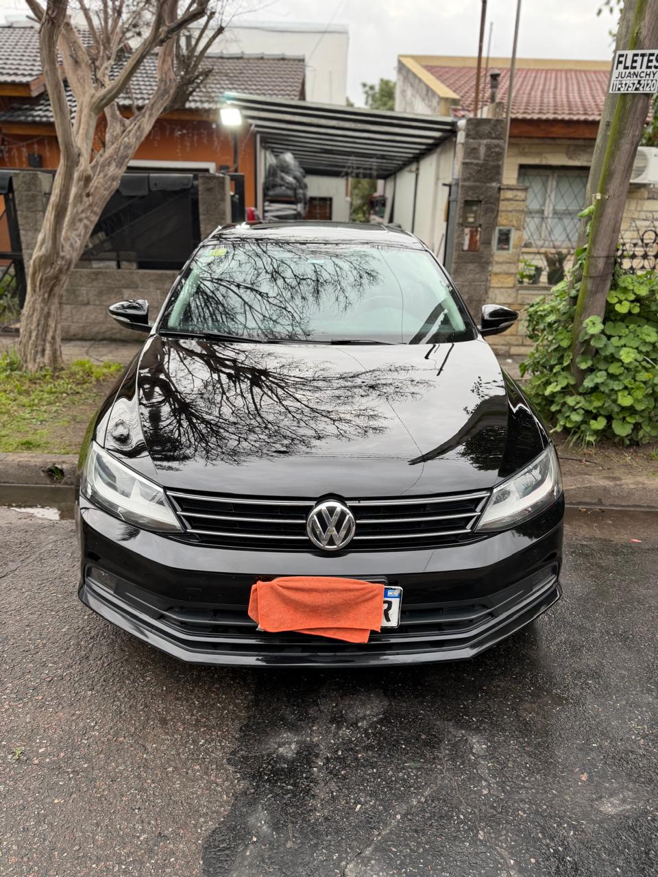 Frente de un Volkswagen negro con brillo espejo tras el lavado premium